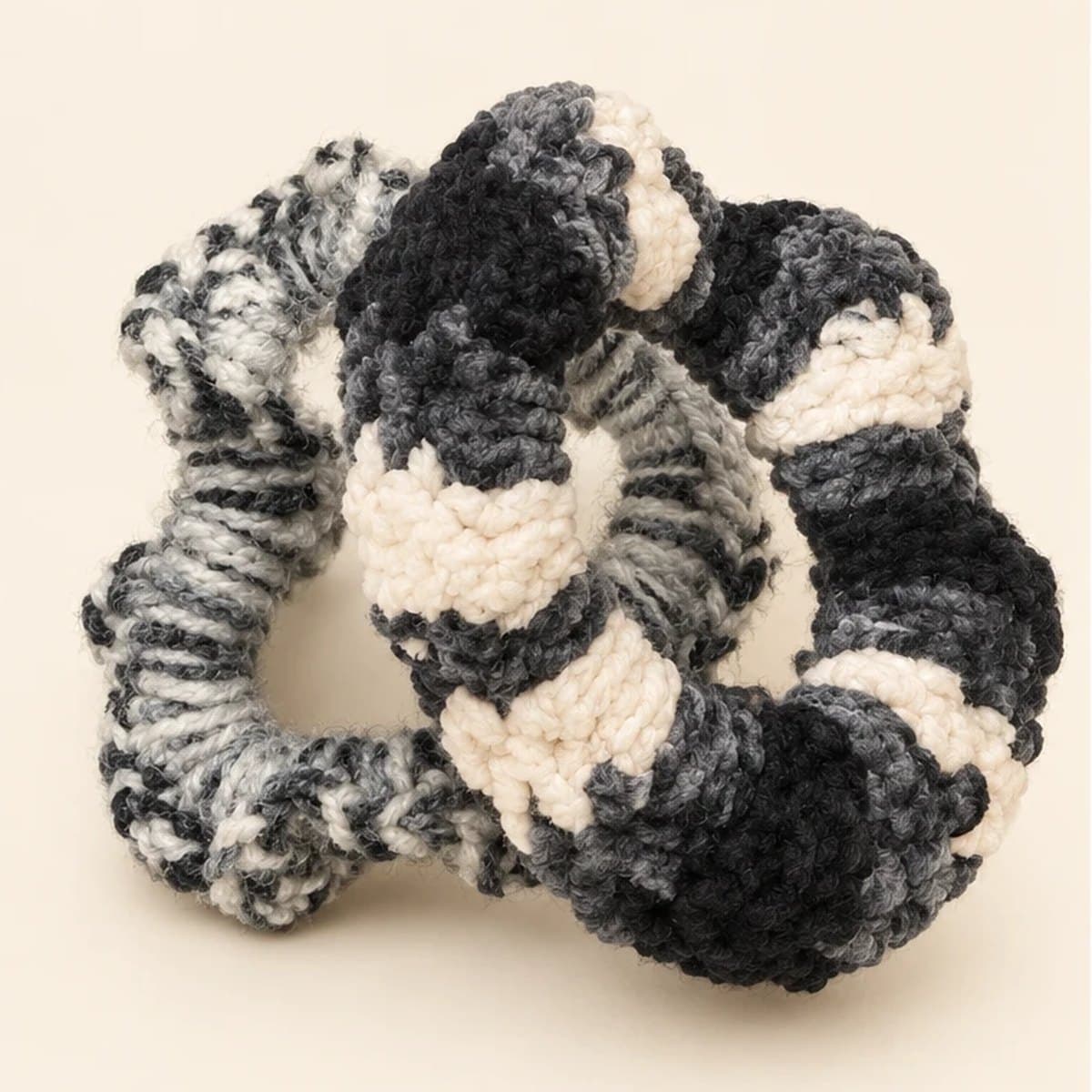 Striped and marled crochet scrunchies together on a cream background
