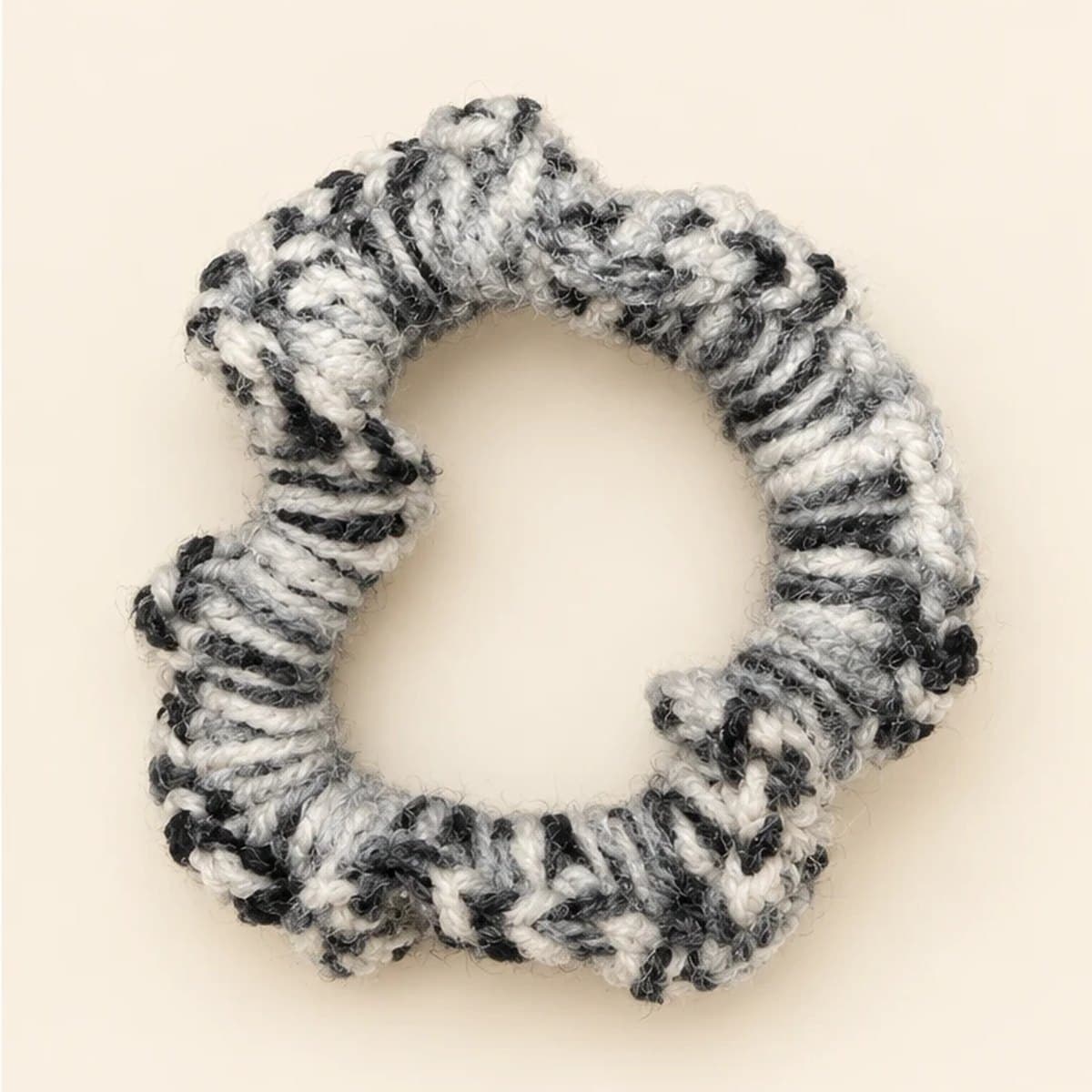 Marled grey and ivory crochet scrunchie on a cream background